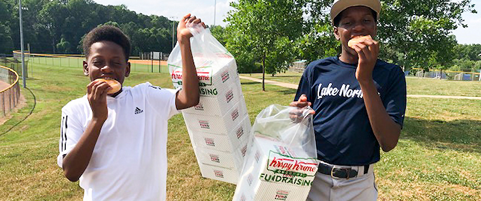 boys eating doughnuts and holding boxes of doughnuts